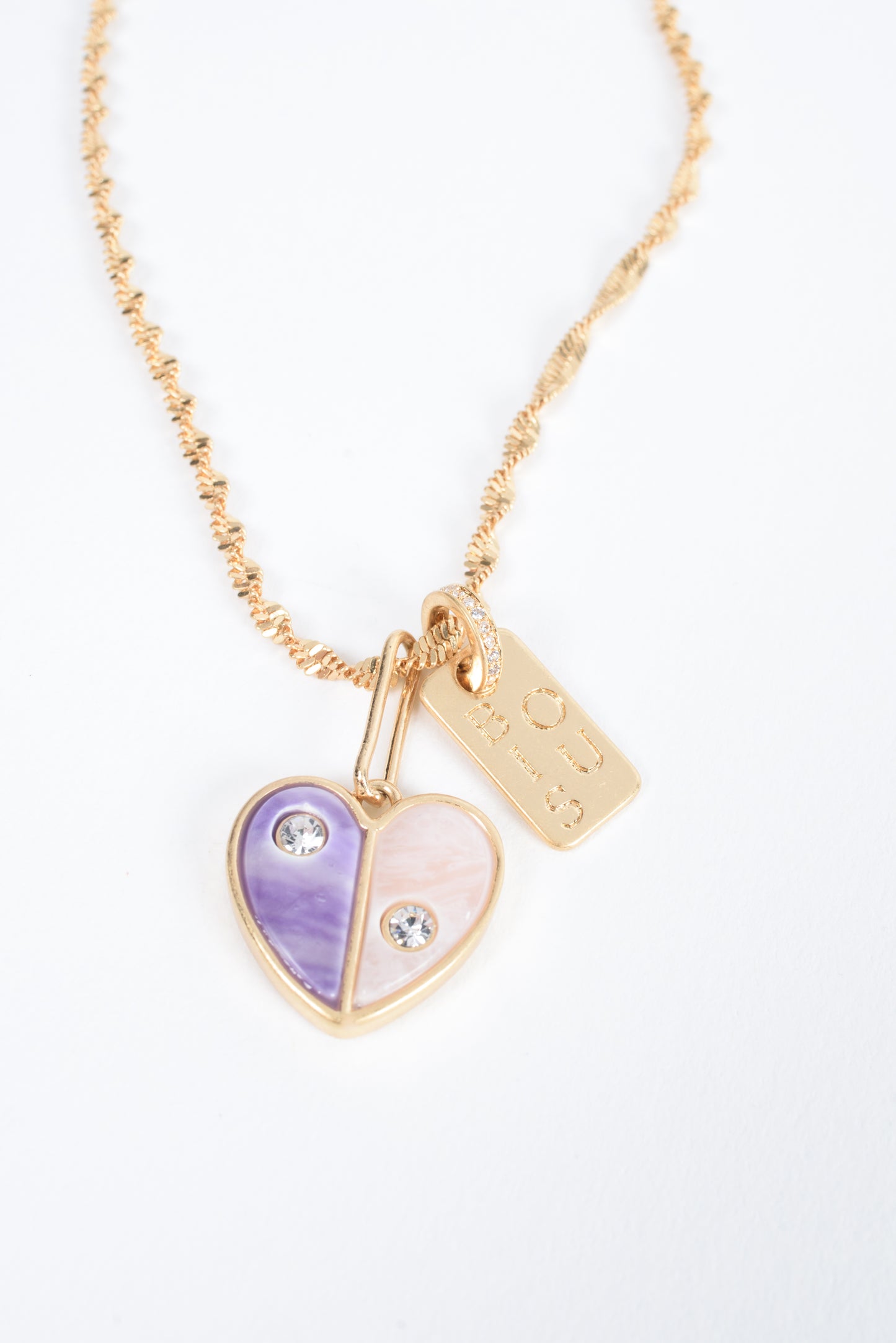 Embrace self-love with the Love Yourself Necklace, featuring a stunning two-tone heart crafted from brass with purple and pearl colored stone inlays. Each side of the heart is adorned with a sparkling zircon stone, symbolizing the balance between strength and tenderness. Paired with the matching Bisous bangle, this necklace is a reminder to cherish yourself and celebrate your unique journey. Designed for versatility, it can be worn alone or layered to inspire confidence and radiance in every version of you.