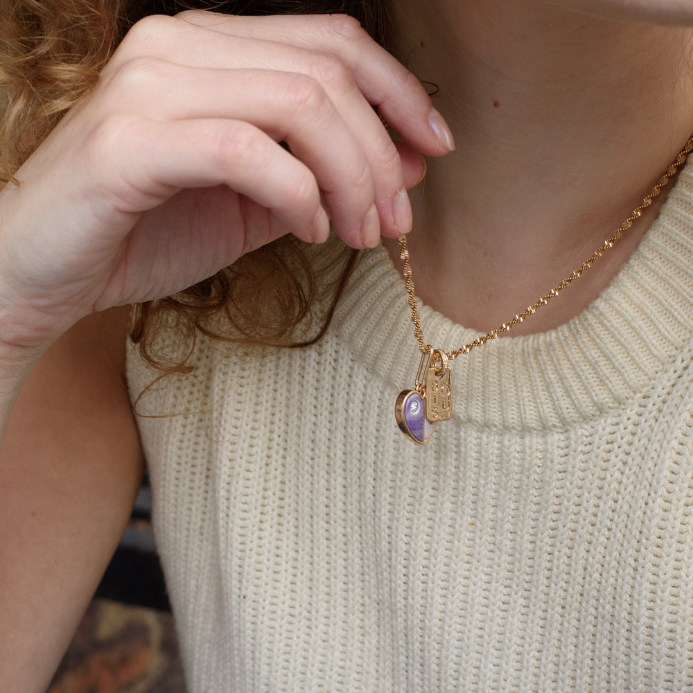 Embrace self-love with the Love Yourself Necklace, featuring a stunning two-tone heart crafted from brass with purple and pearl colored stone inlays. Each side of the heart is adorned with a sparkling zircon stone, symbolizing the balance between strength and tenderness. Paired with the matching Bisous bangle, this necklace is a reminder to cherish yourself and celebrate your unique journey. Designed for versatility, it can be worn alone or layered to inspire confidence and radiance in every version of you.