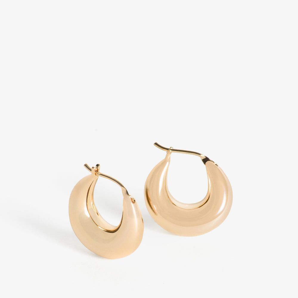 The Everri Day Huggies are a sleek and modern take on the classic hoop earring, inspired by the elegant curve of a half-moon. These solid, half-moon shaped earrings are meticulously crafted and plated with gold, representing balance and serenity. With a minimalist design that hugs the ear closely, they offer a chic look that seamlessly transitions from day to night, adding a subtle celestial charm to any outfit and celebrating personal evolution and style.