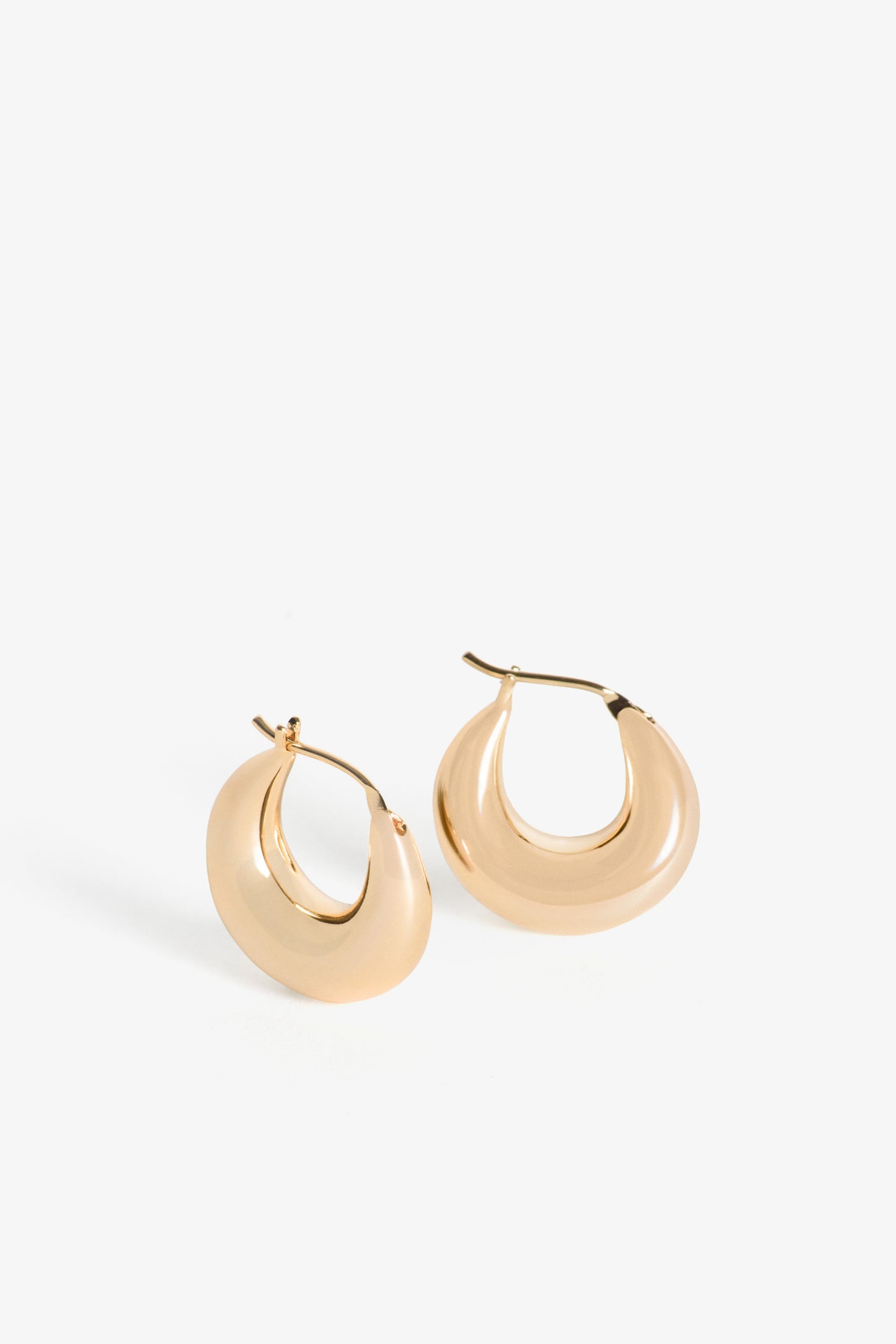 The Everri Day Huggies are a sleek and modern take on the classic hoop earring, inspired by the elegant curve of a half-moon. These solid, half-moon shaped earrings are meticulously crafted and plated with gold, representing balance and serenity. With a minimalist design that hugs the ear closely, they offer a chic look that seamlessly transitions from day to night, adding a subtle celestial charm to any outfit and celebrating personal evolution and style.