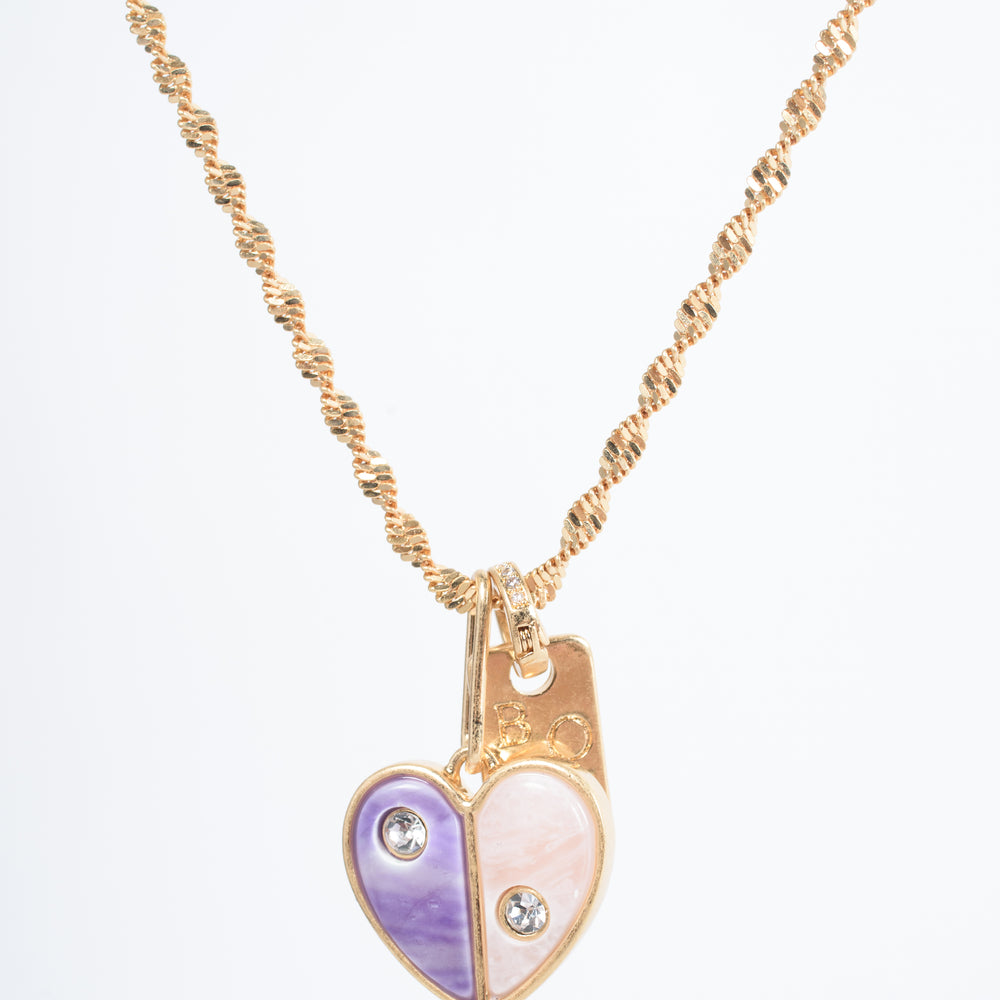 Embrace self-love with the Love Yourself Necklace, featuring a stunning two-tone heart crafted from brass with purple and pearl colored stone inlays. Each side of the heart is adorned with a sparkling zircon stone, symbolizing the balance between strength and tenderness. Paired with the matching Bisous bangle, this necklace is a reminder to cherish yourself and celebrate your unique journey. Designed for versatility, it can be worn alone or layered to inspire confidence and radiance in every version of you.